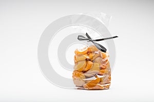 Symbolic scissors in ribbon cut a transparent bag of apricots