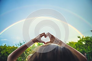 Symbolism of love, rainbow sky, love. heart shaped hands and rainbow in the sky. double rainbow