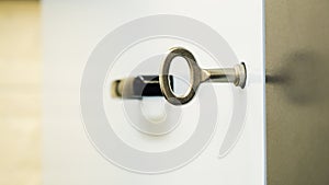 Symbolizing access and security, a modern silver key is inserted into a door lock, with a blurred black handle in the background