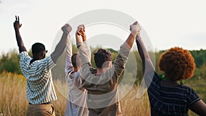 Symbols of friendship. Group of ethnically diverse people standing arm to arm in the middle of a meadow, throwing their