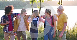 Symbols of friendship. Group of ethnically diverse people standing arm to arm in the middle of a meadow, throwing their