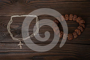 Symbols of religions, a Christian Orthodox cross on a chain around the neck and a Buddhist bracelet lie together on a wooden table