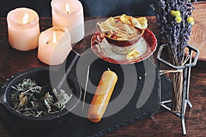 Symbols and sigils carved onto a yellow gold color candlestick, that is laying on a black surface photo