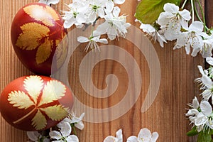 Symbols of spring - Easter eggs dyed with onion peels and cherry blossoms on a wooden background with copy space