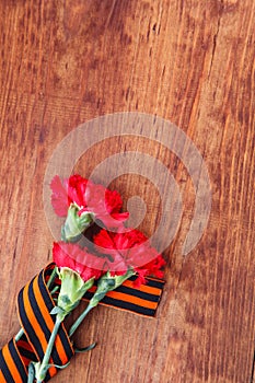 Symbols of Victory in Great Patriotic War three red flower and George ribbon on wooden table