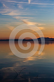 Symmetrcal, beautiful view of Trasimeno lake Umbria, Italy at sunset, with orange and blue tones in the sky