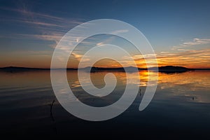 Symmetrcal, beautiful view of Trasimeno lake Umbria, Italy at sunset, with orange and blue tones in the sky