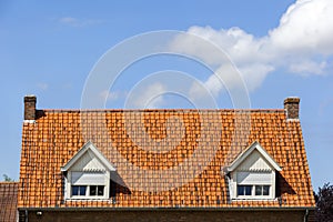 Symmetric red tiled roof with two dormers with rolling shutters