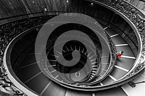 Symmetric view of beautiful circular stairs with a woman in a red dress in a selective color