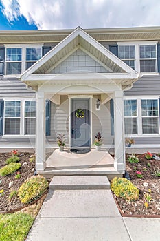 Symmetrical house facade with vinyl wood siding and gray front door