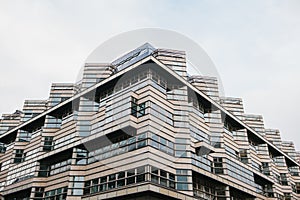 A symmetrical snapshot of a building corner with lots of windows against the sky