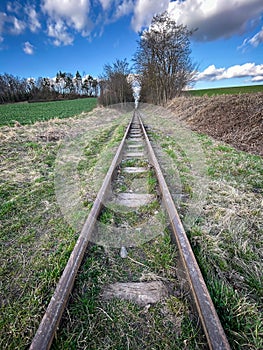 Symmetry narrow gauge railway in spring countryside under blue sky