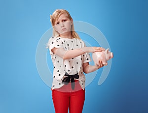 Sympathetic modern girl fondle piggy bank with plaster on blue