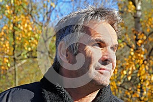 A sympathetic, older man with grey hair in autumn