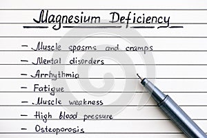 Symptoms of Magnesium Deficiency writing on the list with pen. photo