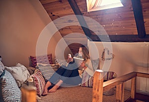 Synching her devices at home. a young woman texting on her smartphone while relaxing in her bedroom at home.