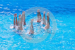 Synchronised swimming. Beautiful lean female legs in the water of a swimming pool. Concept of beauty, artistry