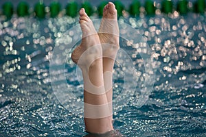 Synchronized Swimmers point up out of the water in action. Synchronized swimmers legs movement. Synchronized swimming team