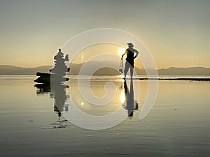 The synergistic state of the photographer at the lake during the serene sunset hours. Fun person accompanied by Zen stones,