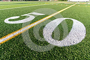 Synthetic turf football field fifty, 50, yard line in white.