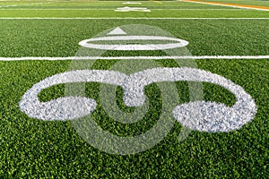 Synthetic turf football field thirty, 30, yard line in white.