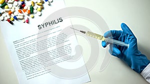 Syphilis diagnosis written on paper hand holding medication in syringe treatment