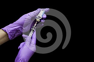 Doctor hands with rubber gloves holding disposable plastic syringe