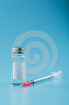 Syringe and ampoule with a vaccine against viruses and diseases on a blue background photo