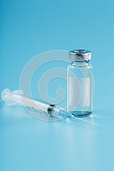 Syringe and ampoule with a vaccine against viruses and diseases on a blue background photo