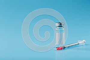 Syringe and ampoule with a vaccine against viruses and diseases on a blue background photo