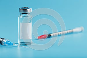 Syringe and ampoule with a vaccine against viruses and diseases on a blue background. photo