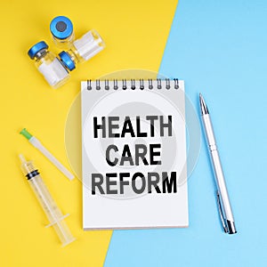 A syringe, ampoules and a notebook with the inscription - HEALTH CARE REFORM