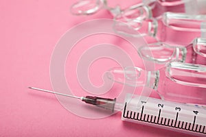 Syringe and ampoules on a pink background