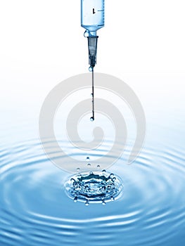 The syringe with the blue liquid on the blue water background with drops and splash