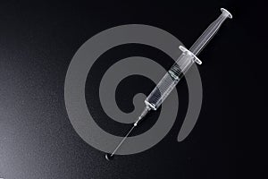 The syringe is filled with liquid and drips separately on a black background