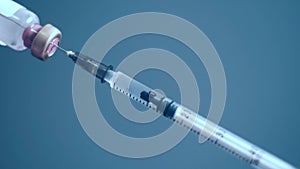 Syringe is filling with vaccine from a bottle, close-up.