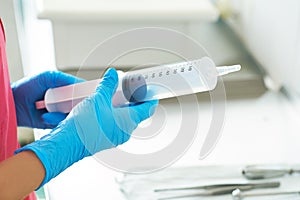 Syringe for gastric lavage in the hands of a nurse in the operating room. Nurse preparing medical instruments for