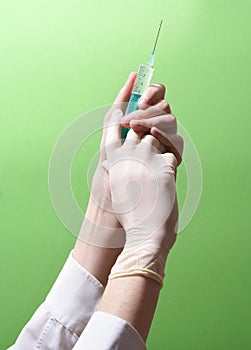 Syringe in hands on green