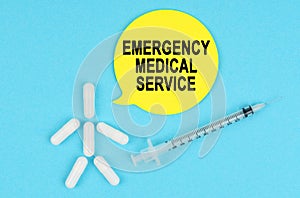 Syringe, human figure made of pills and paper sticker with the inscription - EMERGENCY MEDICAL SERVICE