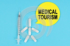 Syringe, human figure made of pills and paper sticker with the inscription - MEDICAL TOURISM