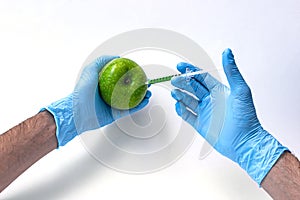 Syringe injection into a apple with sorbic acid waiting for long-term storage of fruit. Genetic modified foods.  on white
