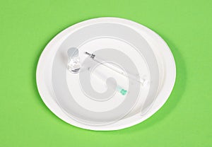 Syringe injection or medical needle on simple plate isolated on green