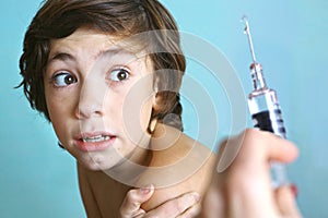 Syringe with injection vaccination. Boy is afraid.