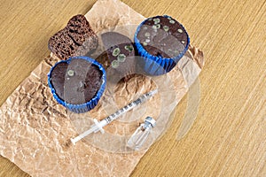 Syringe with insulin next to moldy muffins and ampoule