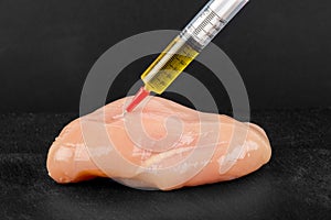 Syringe with liquid being injected to a piece of meat