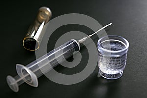 Syringe with liquid medicine container on black