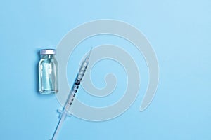 Syringe with medicine from glass vial on light blue background  flat lay. Vaccination against influenza  covid 19  measles