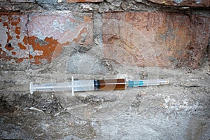 Syringe with a narcotic substance, against the background of an abandoned wall. Addiction concept