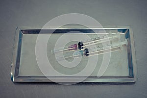 Syringe with needle on a steel tray