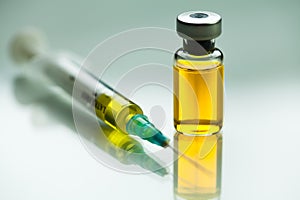 Syringe with needle & vial ampoule with yellow liquid photo